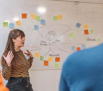 Kursholder snakker foran whiteboard med post-its.