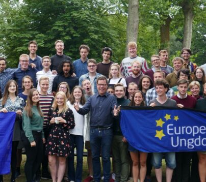 Bildet viser en gruppe ungdommer som smiler mot kameraet. De holder et banner som viser Europeisk Ungdom og et EU-flagg.