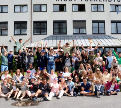 Bildet viser en oppstilt gruppe mennesker som smiler mot kameraet og strekker armene i været. Det er sommer. Bildet er tatt på et arrangement hos Dysleksi Norge.