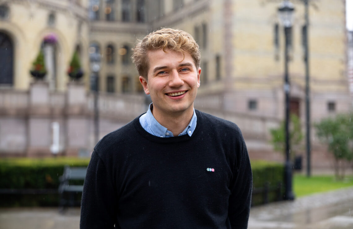 Bilde av styreleder foran Stortinget. Han smiler.