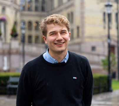 Bilde av styreleder foran Stortinget. Han smiler.
